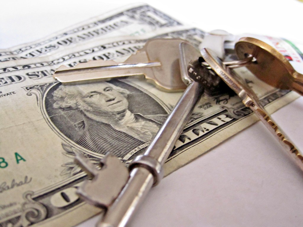 House keys resting on a stack of US banknotes, representing a mortgage down payment