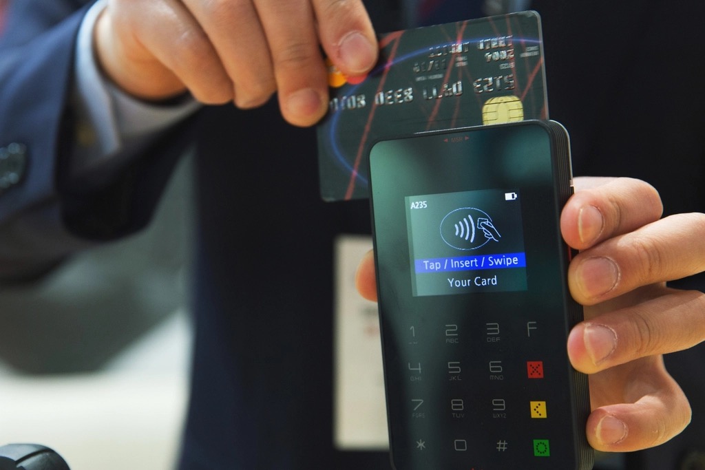 A shopper tapping a payment card at a checkout terminal, illustrating how crypto rewards cards turn everyday spending into Bitcoin cashback