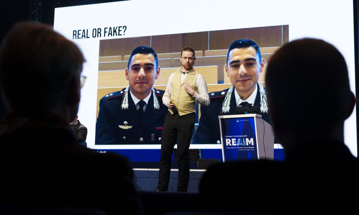 Conference presentation screen asking Real or Fake, showing two versions of the same face side by side