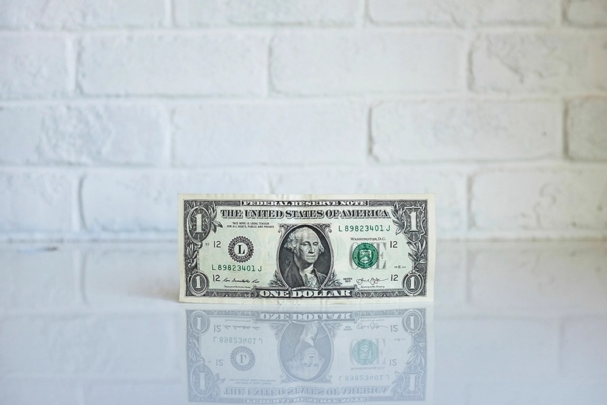 A single US one dollar bill leaning against a wall, standing in for a dollar-denominated token that pays interest